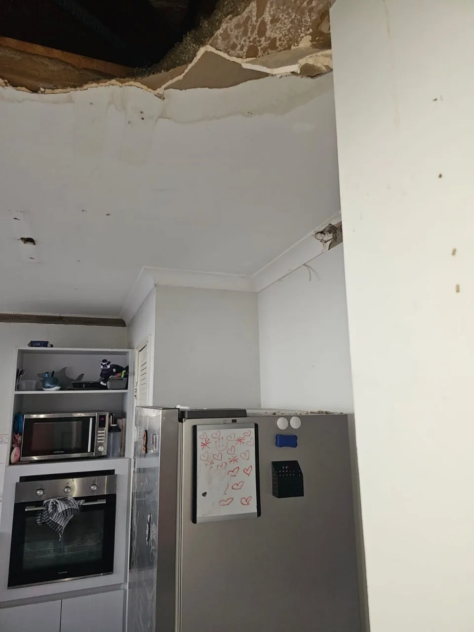 Opened ceiling above a Bassendean kitchen showing dark, sodden insulation and debris sitting on top of the plasterboard that is still in place