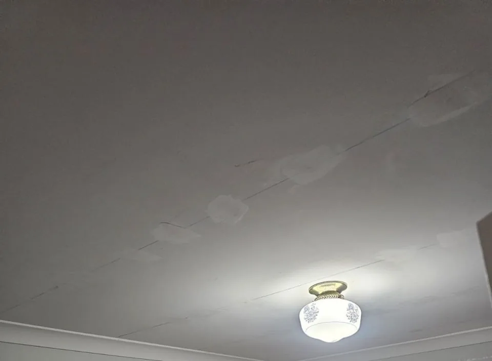 Bedroom ceiling in a Bassendean home with a line of new screw heads patched over in white filler along a plasterboard join