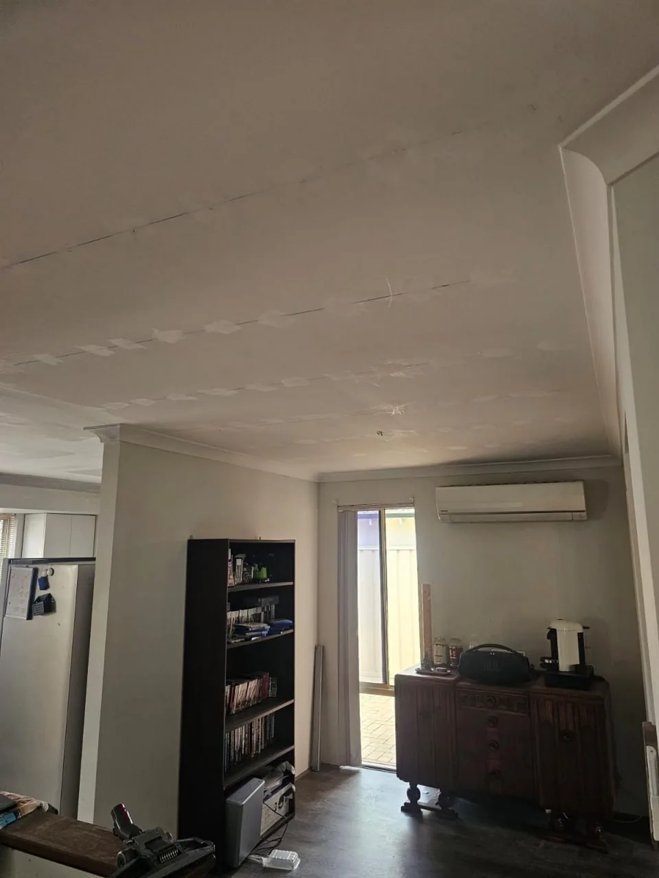Dining area ceiling in a Bassendean home with a row of patched screw heads running along a plasterboard join, beneath a wall-mounted air conditioner