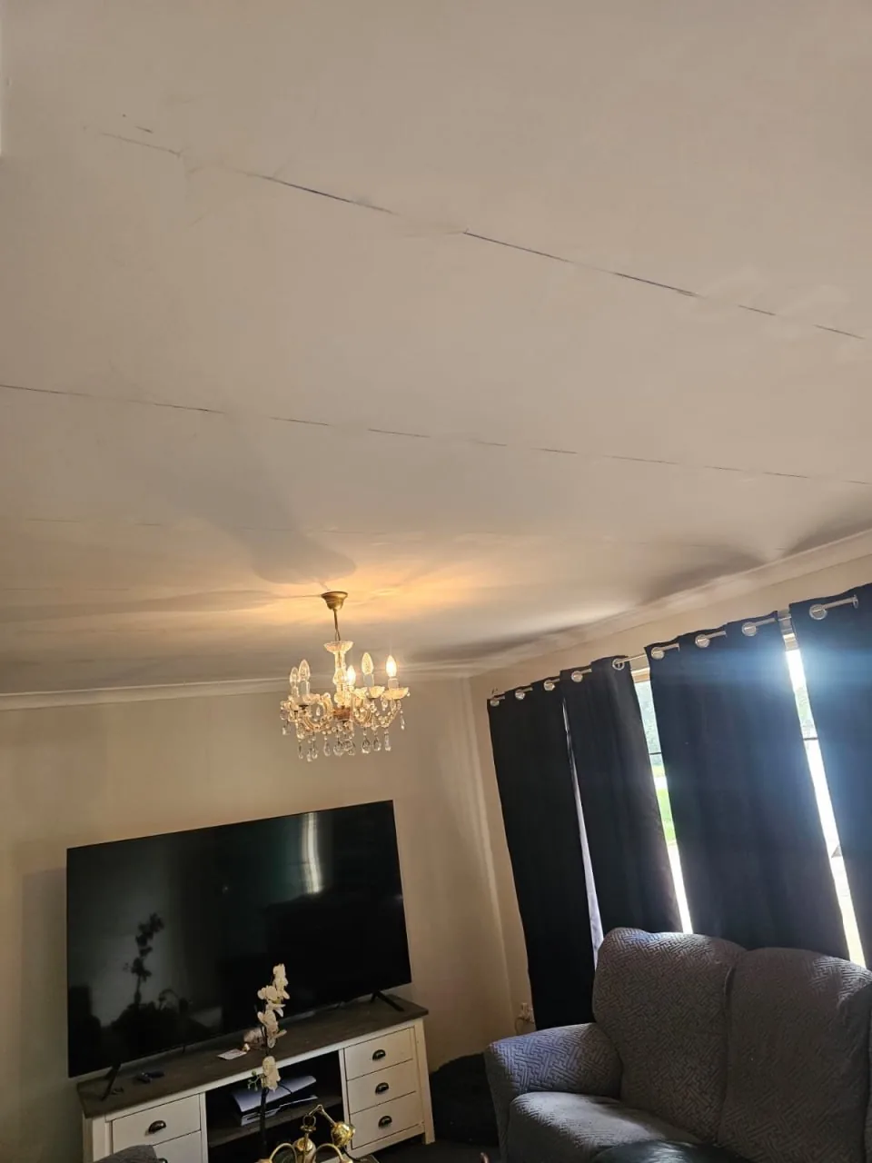 Lounge ceiling in a Bassendean home with a long dark crack running the length of a plasterboard join and grey water staining on either side of it