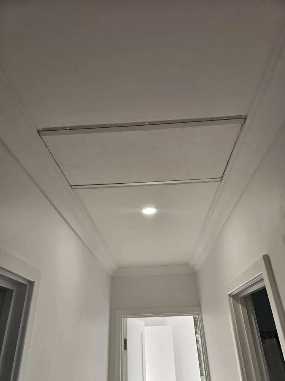 A recessed panel and a downlight set into the new hallway ceiling of a Roleystone house, doorways either side