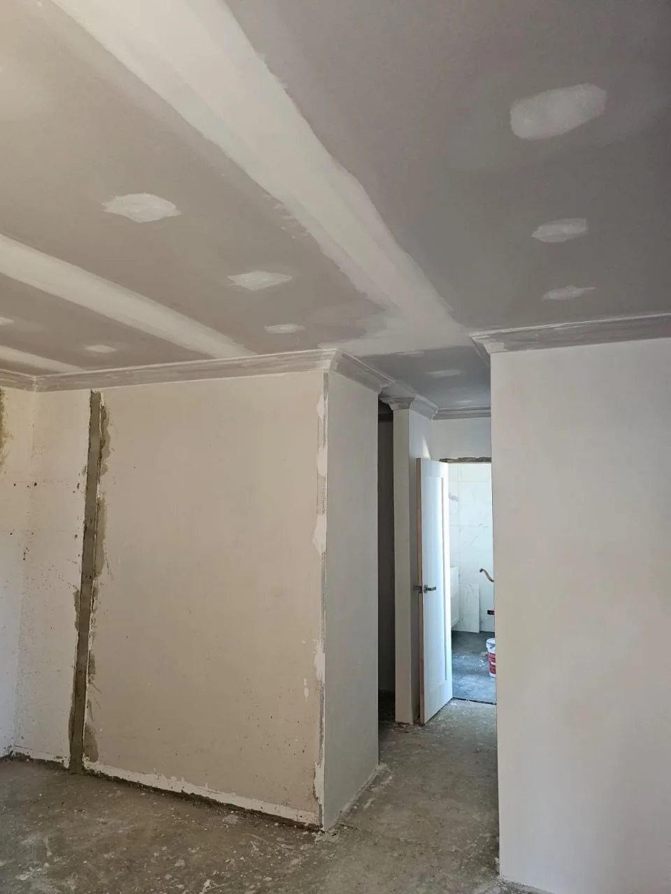 A new bedroom ceiling in a Roleystone house with the downlights cut in and the cornice run, the floor still bare