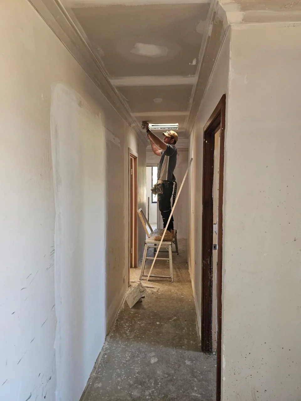 A new hallway ceiling going in at a Roleystone house, with a crew member on a step ladder at the far end of the hall