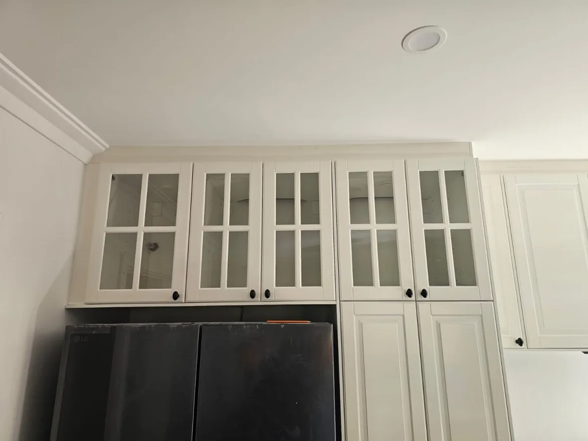The new kitchen ceiling of a Roleystone house running above glass-fronted upper cabinetry and a black range