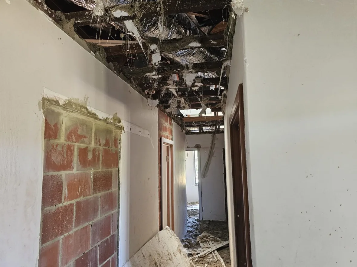 Exposed rafters above a brick nib wall in a Roleystone house with the ceiling gone, debris on the floor below